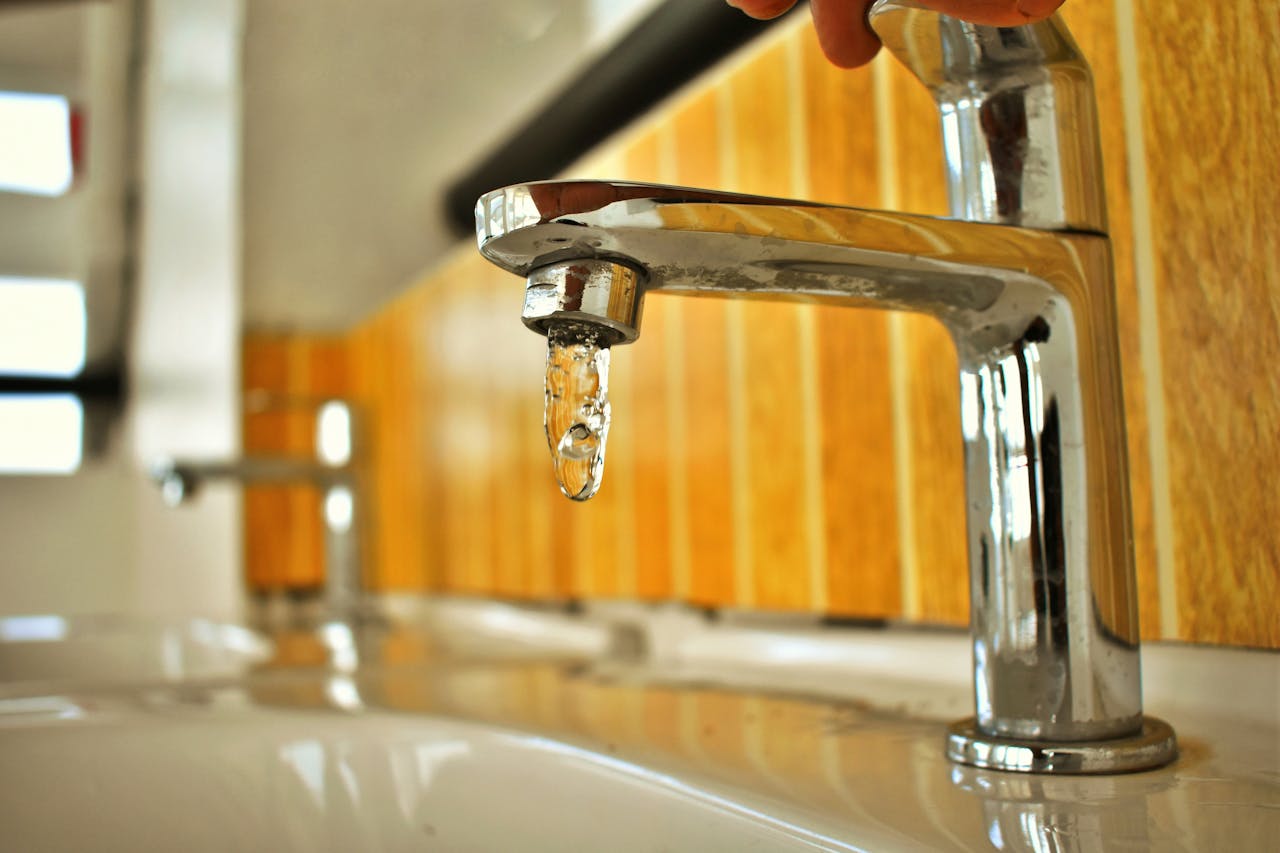 Close-up shot of a chrome faucet with a droplet of water, highlighting its sleek design.